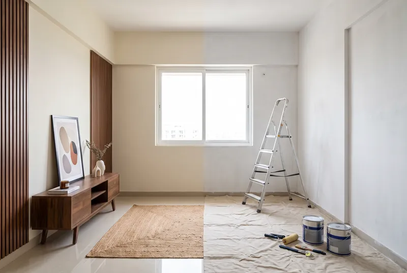 Half-renovated room beside a bare shell with a ladder