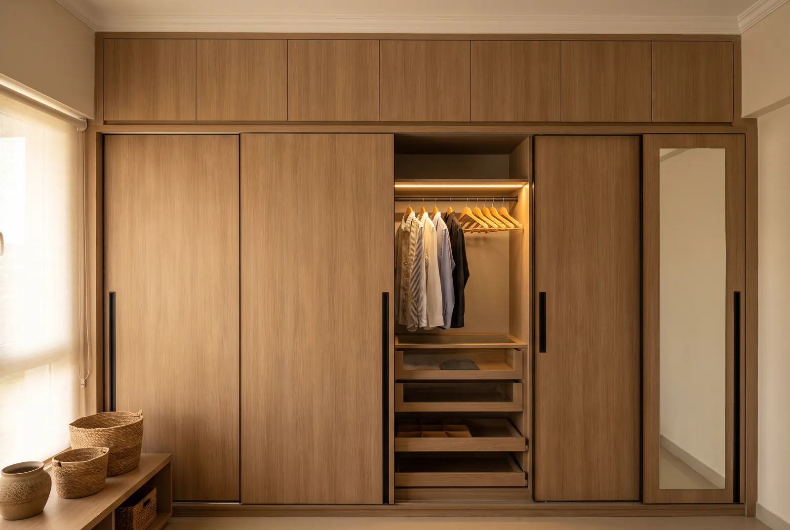 Floor-to-ceiling sliding-shutter wardrobe with loft storage above and internal LED-lit shelving
